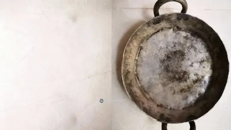 Una padella in ferro con evidenti segni di ruggine su una superficie chiara