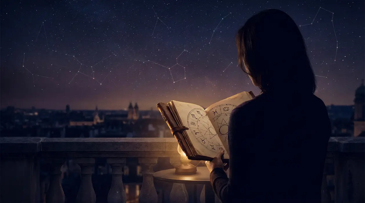 Persona che osserva un libro astrologico sotto un cielo stellato con costellazioni
