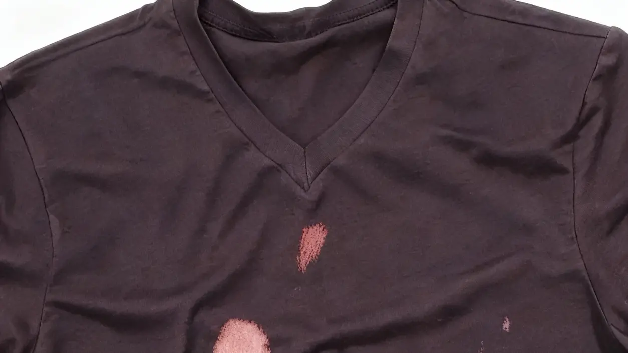 Maglietta scura con evidenti macchie di candeggina sul davanti