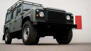 Fuoristrada sportivo verde scuro parcheggiato davanti a un muro con bandiera italiana