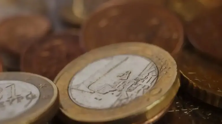 Monete euro in primo piano su una superficie scura, messe a fuoco parziale