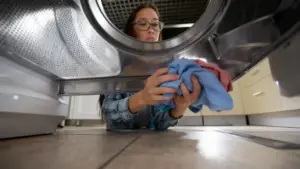 Persona che inserisce vestiti colorati nel cestello di una lavatrice